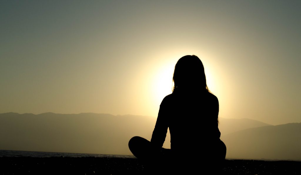 Meditation breathing female silhouette observing sunset sitting cross-legged