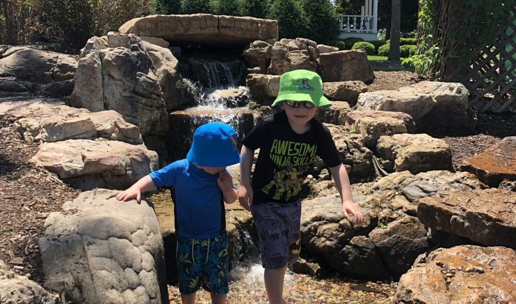 Brothers holding hands walking in natural creek