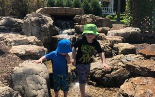 Brothers holding hands walking in natural creek