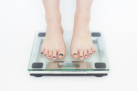 Bare feet on bathroom glass scale white background