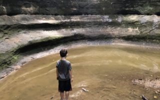 Boy contemplating cave water cavern Starved Rock solitary lonely