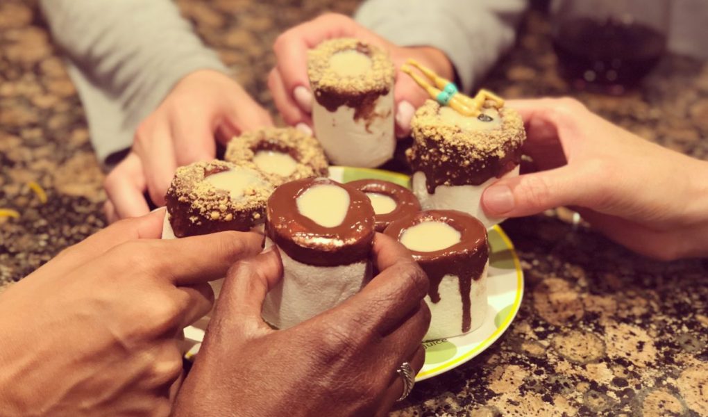 Hands holding shots together cheers marshmallow s'mores shooters