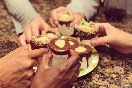 Hands holding shots together cheers marshmallow s'mores shooters