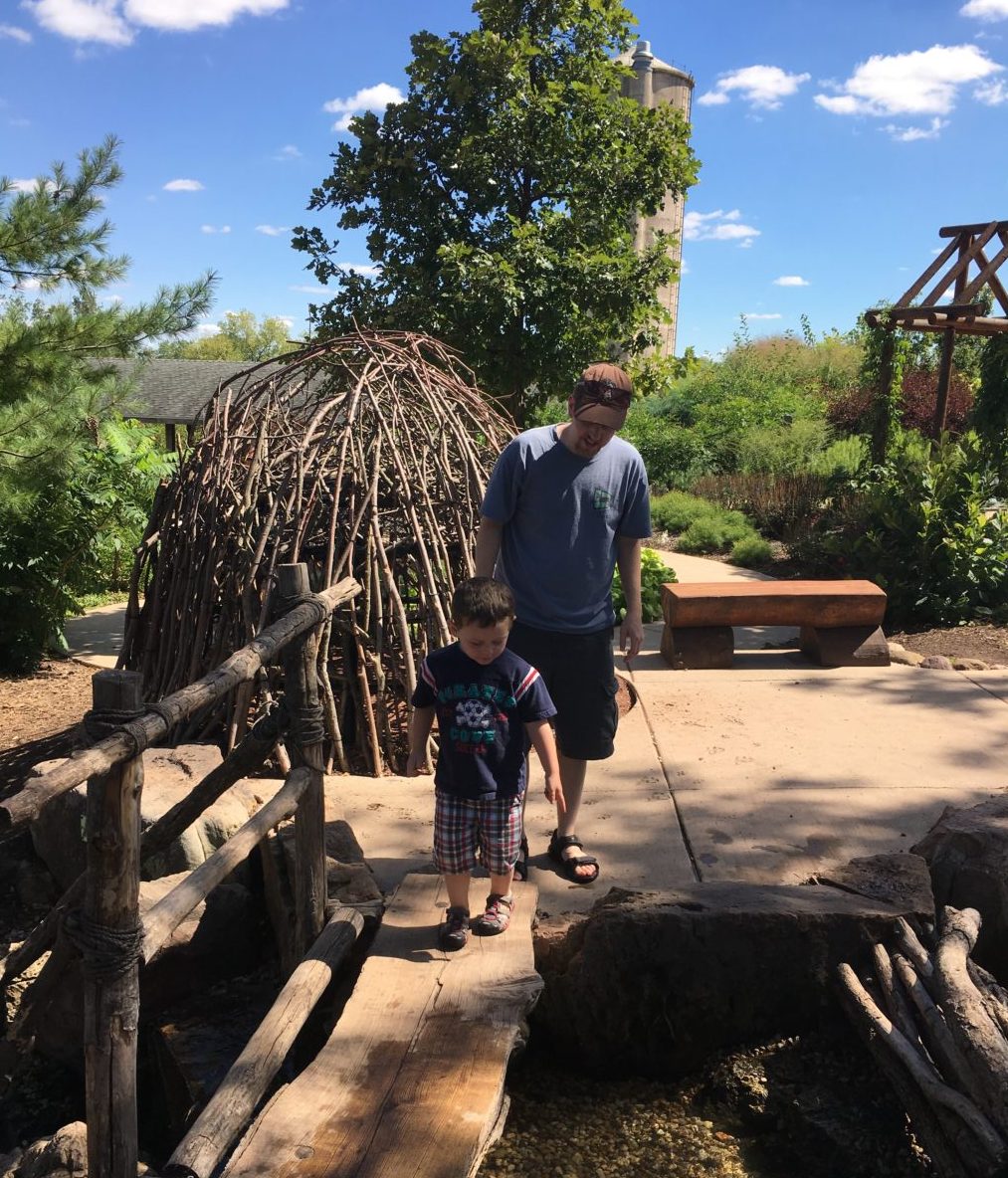 Father and son exploring nature playground bridge