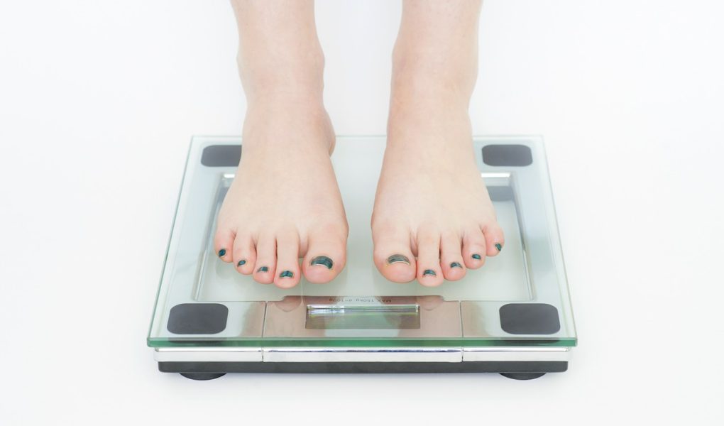 Bare feet on bathroom glass scale white background